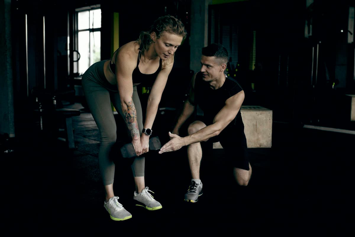 A coach showing a member how to hold a dumbbell for a hinge